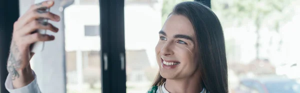 Positive nonbinary designer holding smartphone in office, banner — Fotografia de Stock