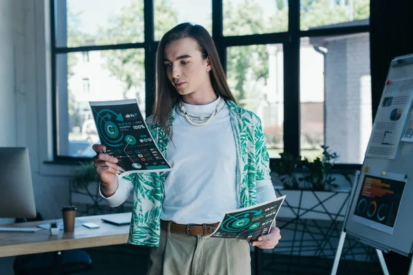 Young queer designer holding green charts in creative agency — Foto stock