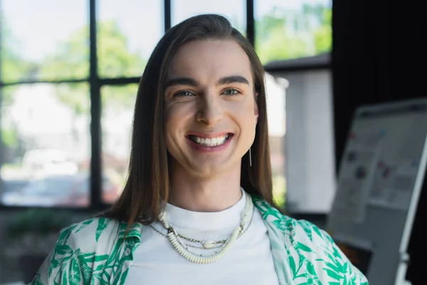 Positive nonbinary person looking at camera in office - foto de stock
