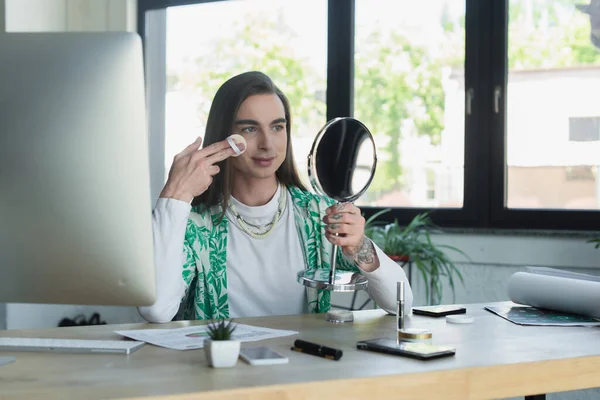 Квір-людина, що застосовує макіяж біля пристроїв у творчому агентстві в офісі — стокове фото