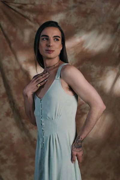 Young nonbinary person in dress posing on abstract background — Stock Photo