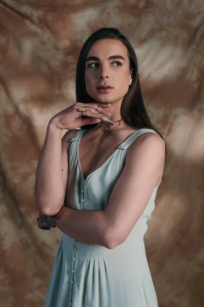 Brunette queer person in sundress looking away on abstract background — Photo de stock