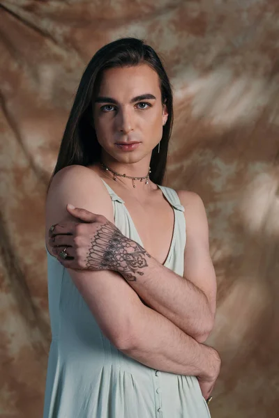 Portrait of brunette queer person in sundress looking at camera on abstract background — Foto stock