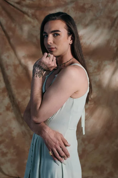 Young queer person in sundress looking at camera on abstract background — Photo de stock