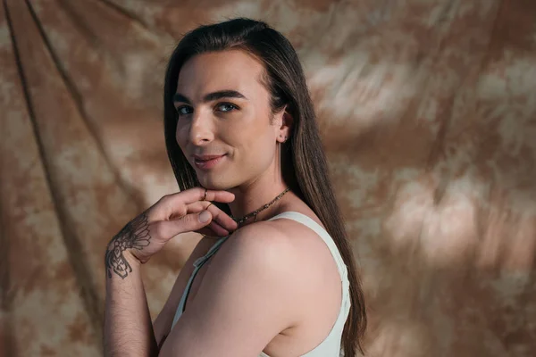 Smiling brunette queer person looking at camera on abstract background - foto de stock