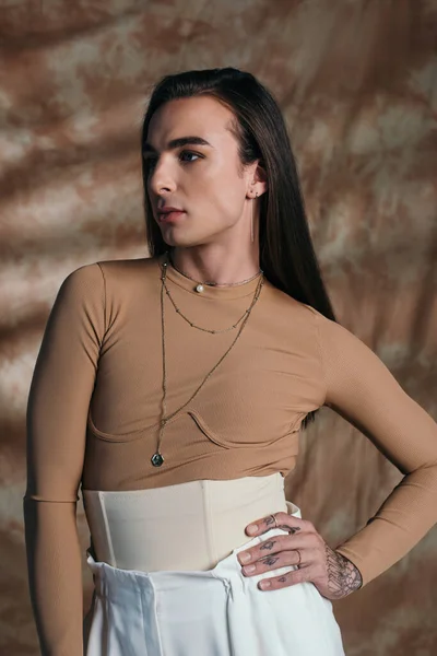 Queer person in corset posing and looking away on abstract brown background — Foto stock