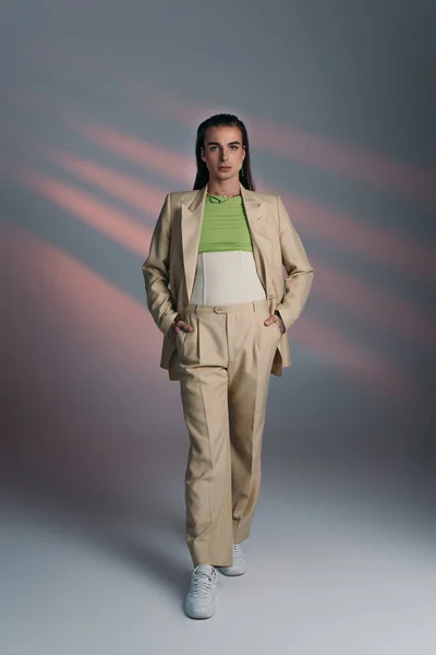 Full length of nonbinary model in suit and corset standing on abstract background - foto de stock