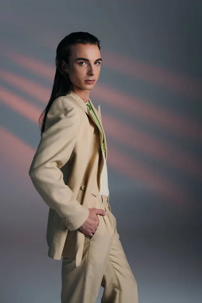 Stylish queer model in suit looking at camera on abstract background — Stockfoto