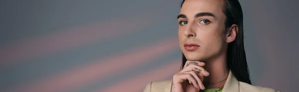 Young queer model touching chin and looking at camera on abstract background, banner — Fotografia de Stock