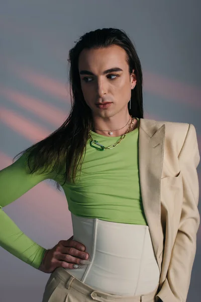 Brunette queer model in corset and jacket looking away on abstract background — Photo de stock