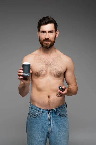 Без сорочки чоловік з бородою тримає дезодорант ізольовано на сірому — стокове фото