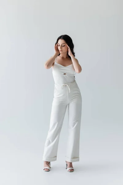 Full length of brunette model in white clothes standing on grey background — Foto stock