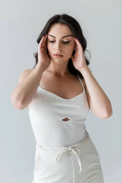 Brunette model touching forehead and looking away isolated on grey — Stock Photo