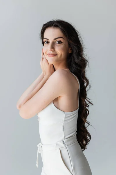 Pretty long haired model smiling at camera isolated on grey — Stockfoto