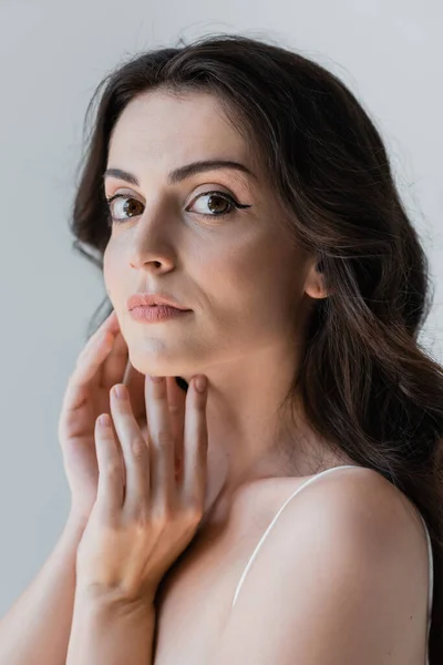 Portrait of brunette woman with visage looking at camera isolated on grey — Stockfoto