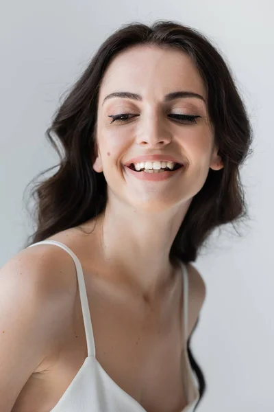 Smiling woman with makeup looking away isolated on grey — Stock Photo