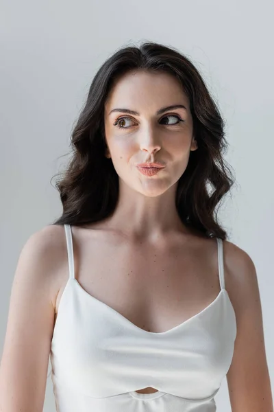 Portrait of sly woman in white top isolated on grey — Stock Photo