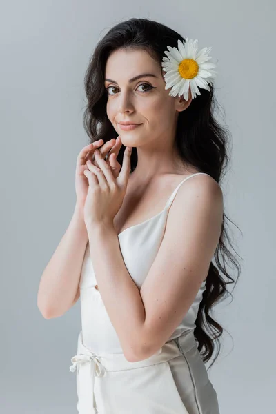 Pretty woman with chamomile in hair looking at camera isolated on grey — Stock Photo