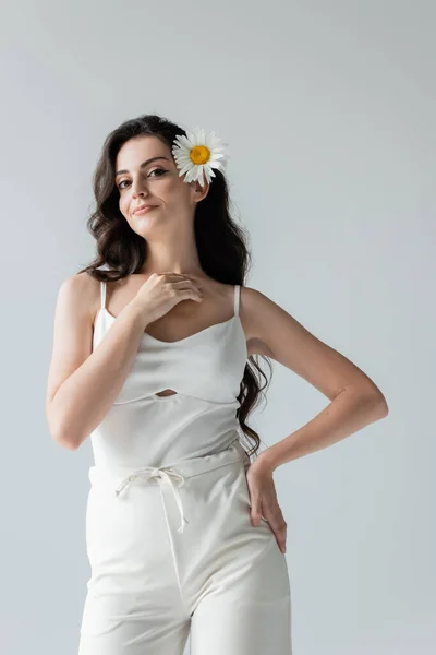 Smiling model in white clothes and chamomile in hair isolated on grey — Stock Photo