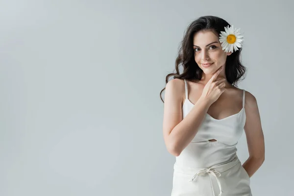 Pretty brunette woman with chamomile in hair posing isolated on grey — Photo de stock