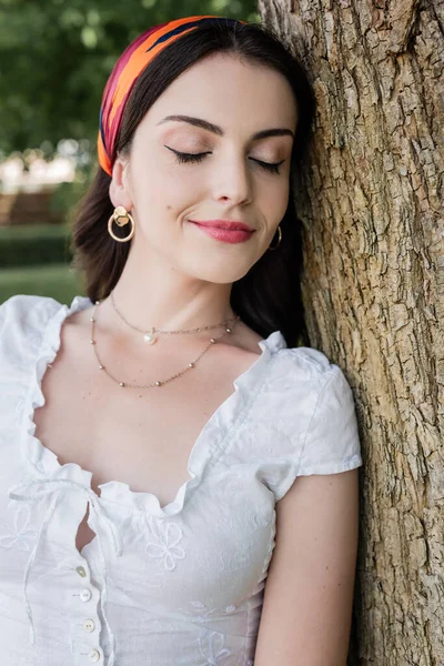 Portrait of stylish woman with makeup standing near tree in park — Stock Photo