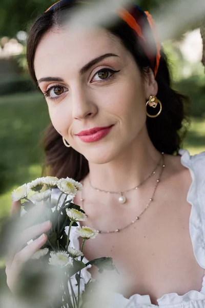 Portrait of pretty brunette woman holding daisies in park — Photo de stock