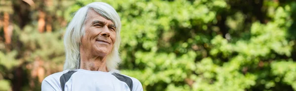 Happy senior man in t-shirt looking away in green park, banner — Stock Photo