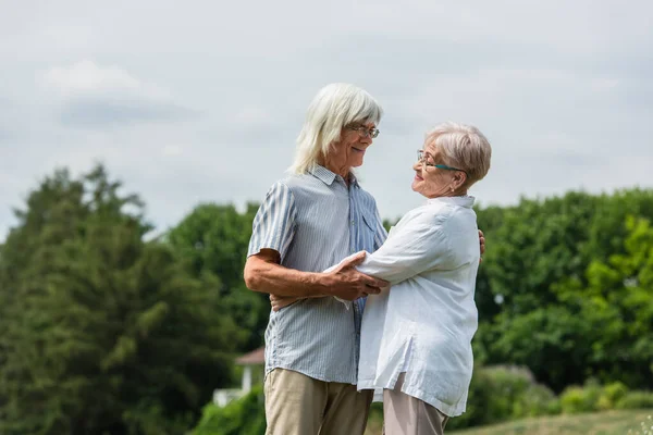 Happy senior husband and wife with grey hair hugging in summer — Foto stock