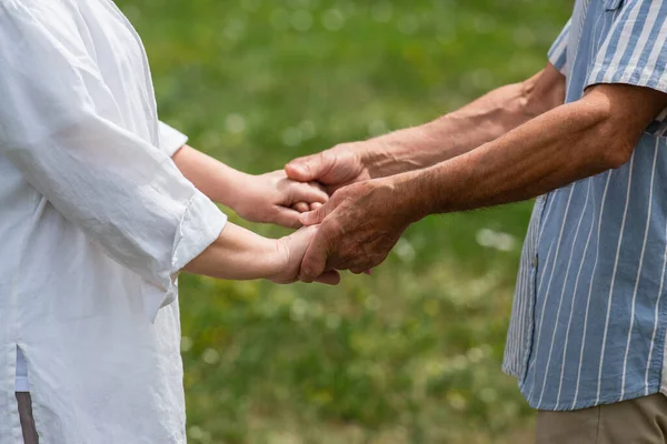 Cropped view of senior husband and wife holding hands in summer — Stock Photo