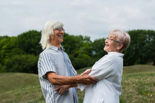 Happy senior couple with grey hair looking at each other and smiling outside — Stockfoto