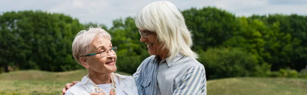 Smiling senior couple in glasses hugging and looking at each other, banner — Stock Photo