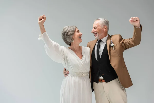 Excited couple of mature newlyweds looking at each other isolated on grey — Foto stock