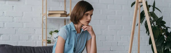 Pensive brunette woman sitting in living room at home, banner — Stock Photo