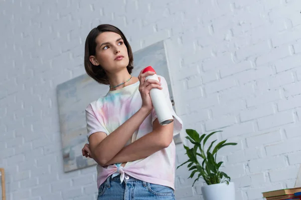 Low angle view of woman holding air freshener in living room - foto de stock