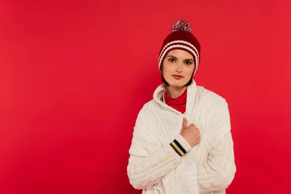 Young woman in knitted clothes looking at camera isolated on red — Stockfoto
