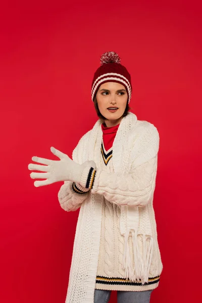 Young woman in warm clothes wearing gloves isolated on red — Photo de stock