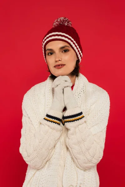 Young woman in knitted sweater and gloves looking at camera isolated on red — Photo de stock