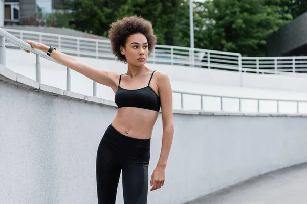 Sportive african american woman with curly hair looking away on stadium - foto de stock