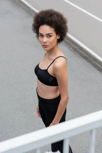 High angle view of african american woman in black sports bra looking at camera - foto de stock