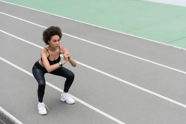 Athletic african american woman in white sneakers doing sit ups with clenched hands — Fotografia de Stock