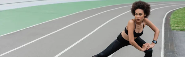 Sportive african american woman with curly hair doing side lunge exercise, banner — Foto stock