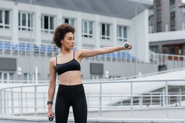 Athletic african american woman with outstretched hand working out with dumbbells — Fotografia de Stock