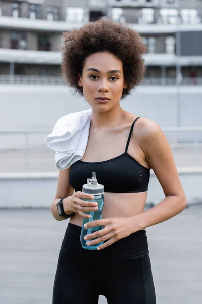 Young african american sportswoman with white terry towel and sports bottle — Foto stock