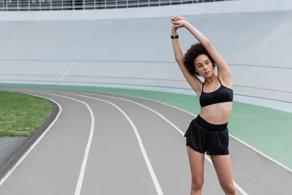 Young african american sportswoman stretching on stadium — Foto stock