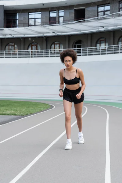 African american sportswoman running on track of stadium - foto de stock