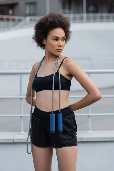 Fit african american sportswoman with jump rope looking away on stadium — Stock Photo