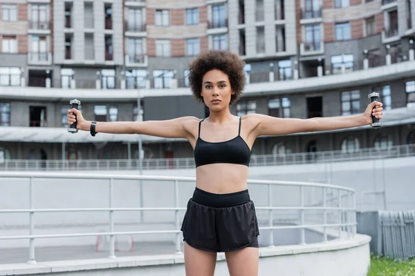 African american sportswoman exercising with dumbbells on stadium at daytime — Stock Photo