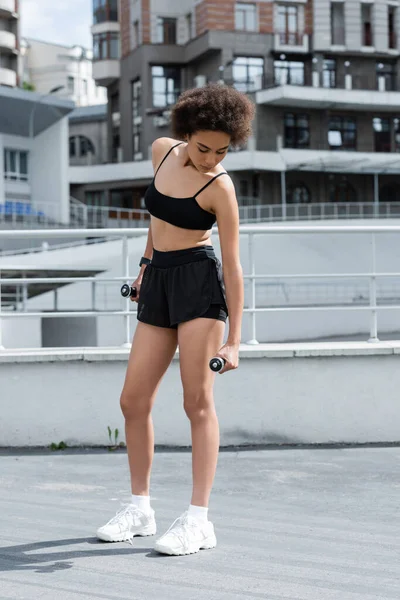 African american woman in sportswear training with dumbbells on stadium — Fotografia de Stock