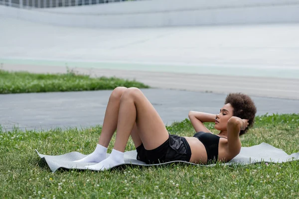 African american sportswoman training on fitness mat on stadium — Stockfoto
