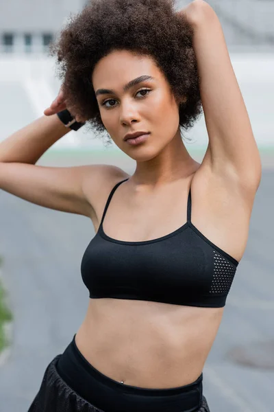 Portrait of african american sportswoman in black top looking at camera outdoors — Stockfoto